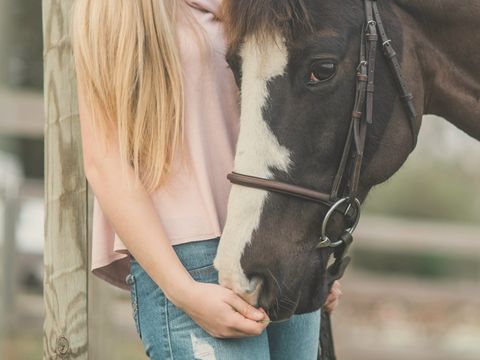A woman with her arms around a black and white horse